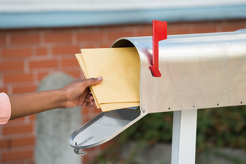 Person placing mail into mailbox